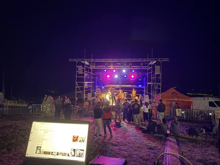 Festival de rock en plein air, scène et public, ambiance nocturne colorée