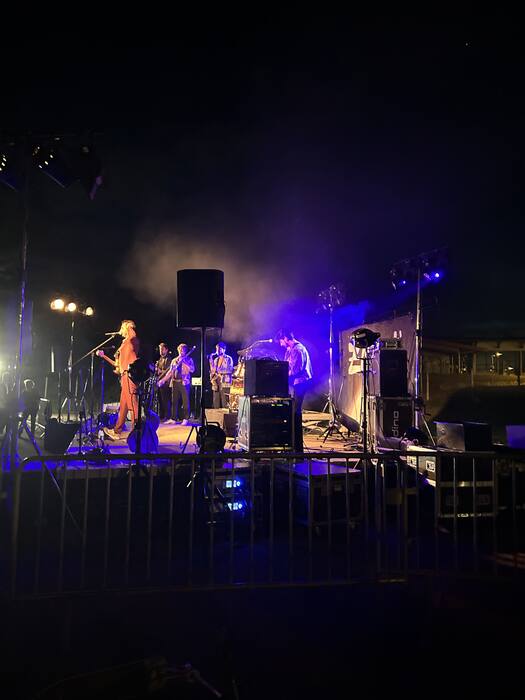 Groupe sur scène en extérieur, éclairage bleu, ambiance de festival