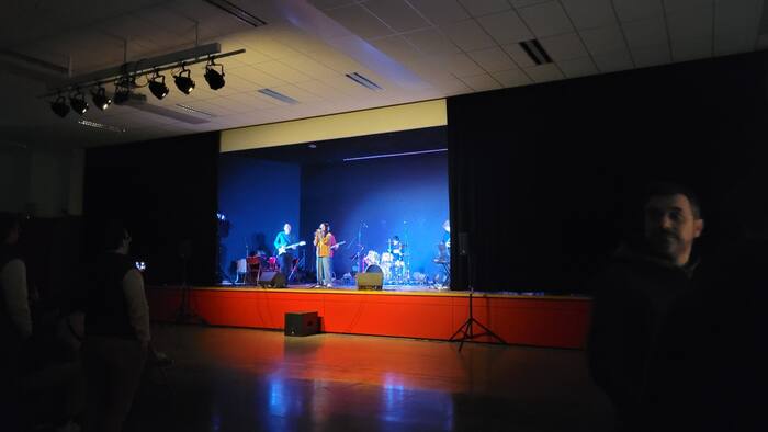 Groupe de musique sur scène dans une salle des fêtes, éclairage bleu